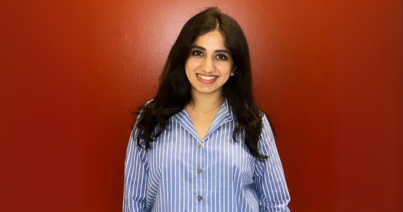 Disha stands in front of orange wall to take a photo